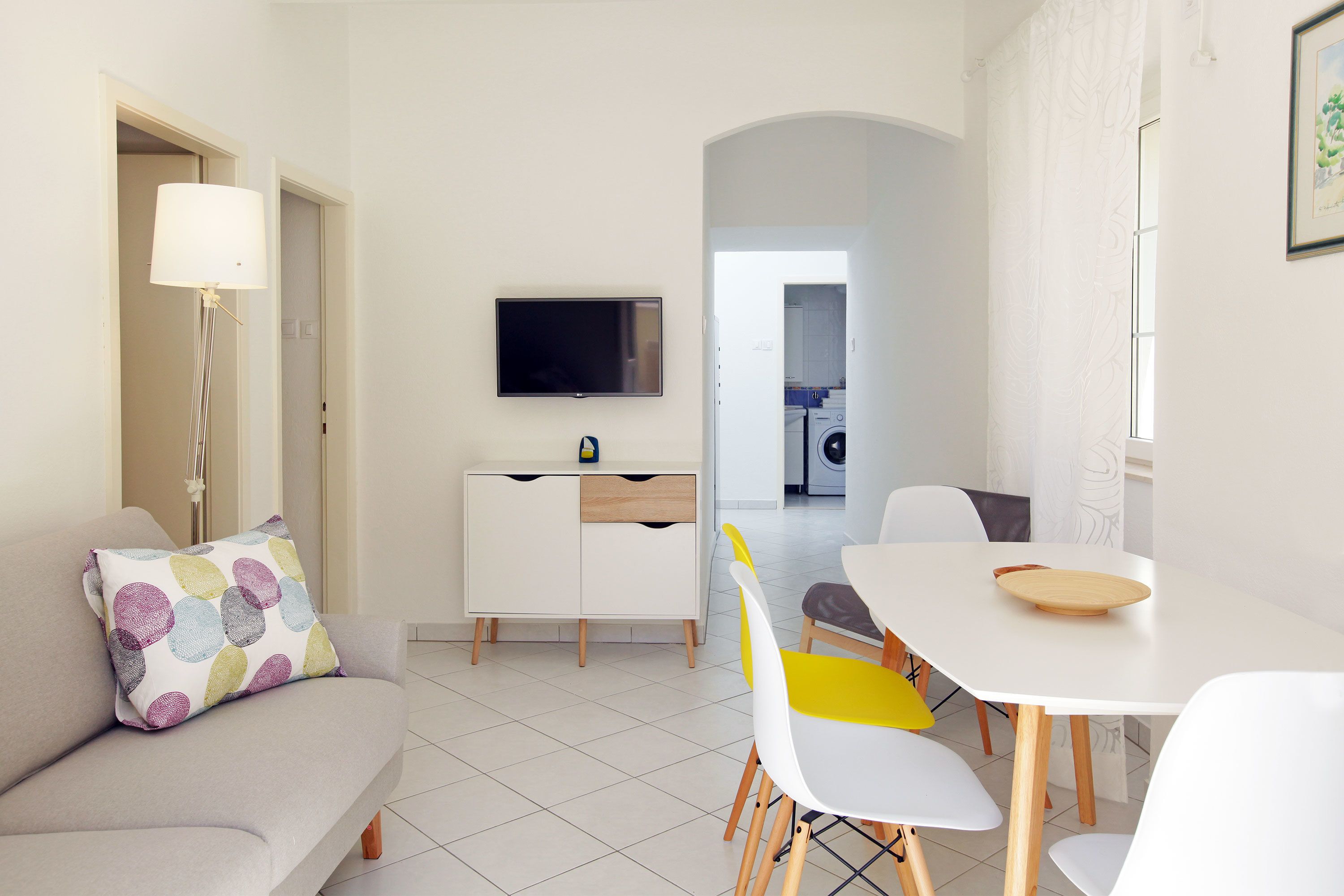 A modern living room with a sofa, a dining table, and a TV.