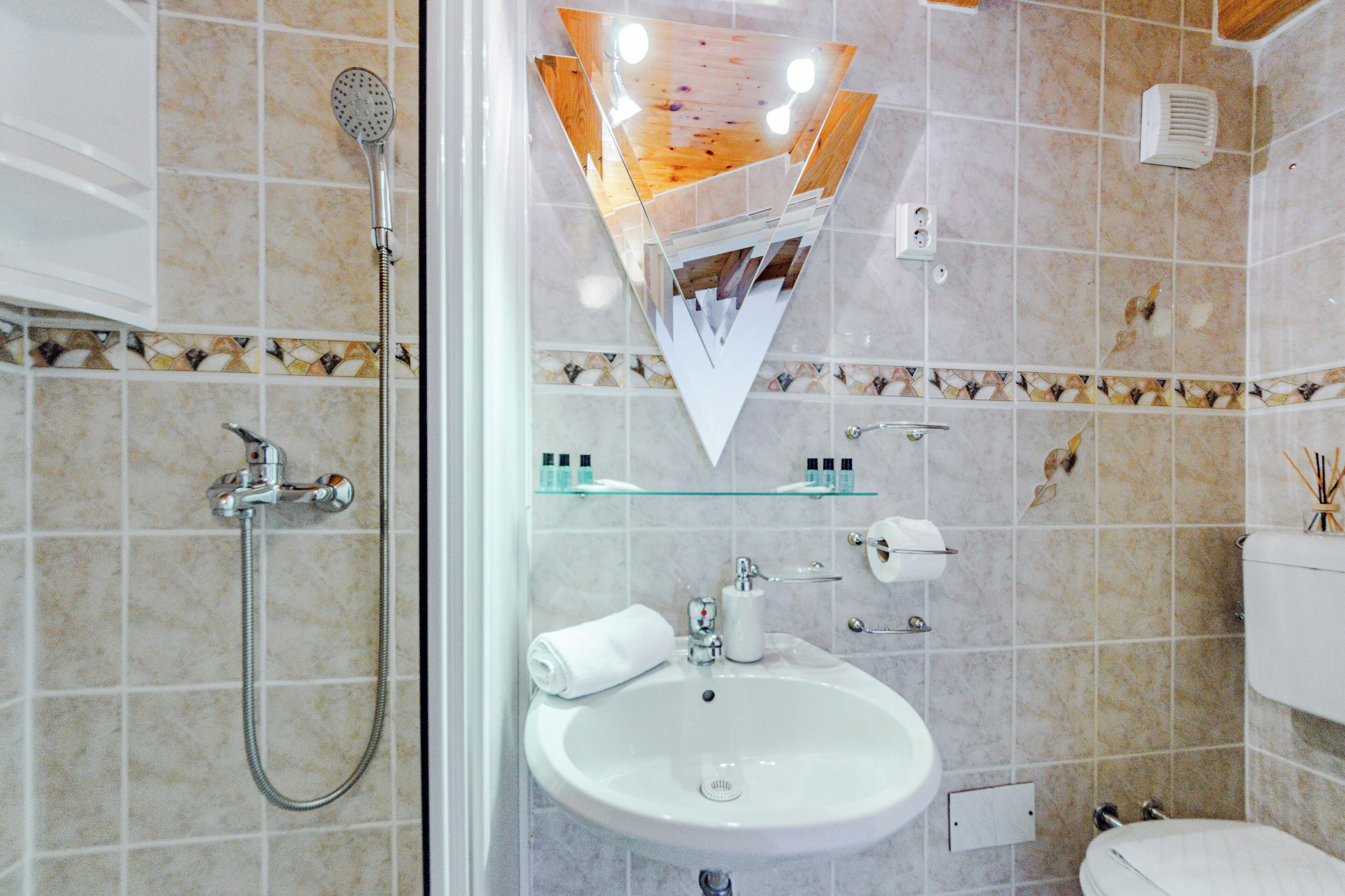 A bathroom with a glass shower enclosure, a sink, and a toilet.