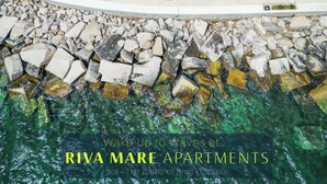 An aerial view of Riva Mare Apartments with stone buildings, a paved street, and a rocky shoreline. - Luxury Seaside Apartments (Bol)