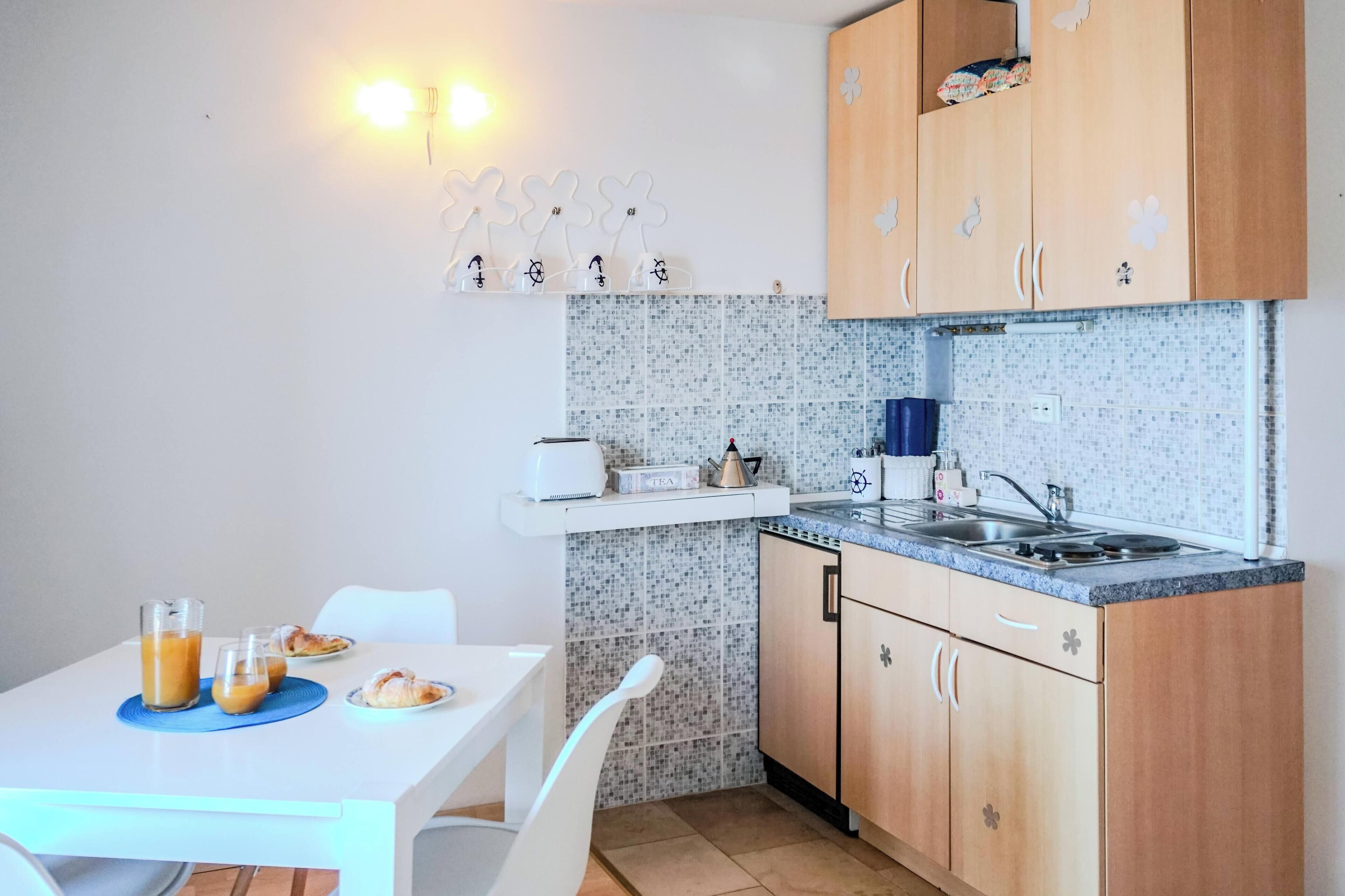 A compact kitchen with a white countertop, wooden cabinets, and a tiled backsplash.