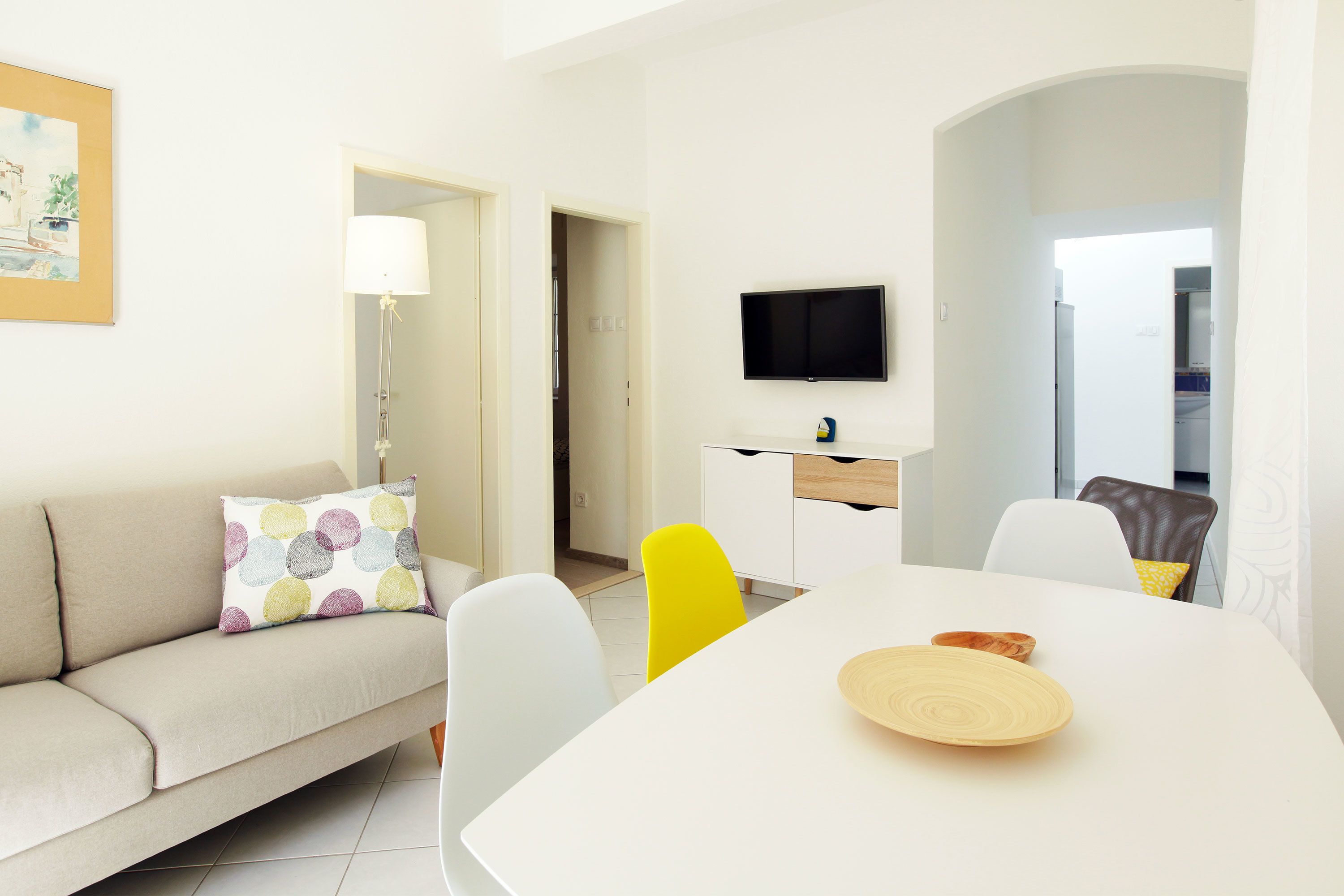 A modern living room with a sofa, a dining table, and a TV.