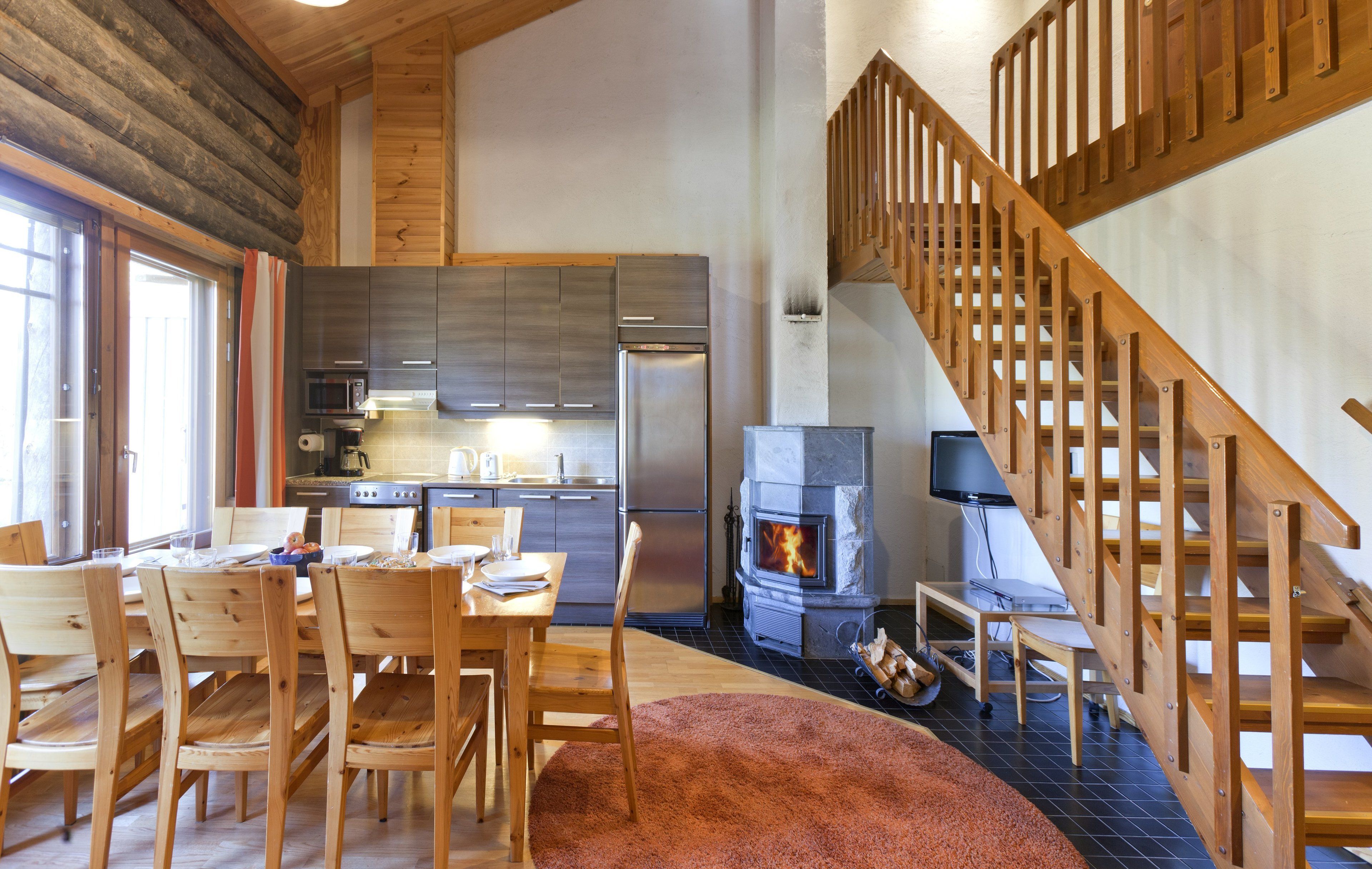 Une cuisine spacieuse équipée d’appareils électroménagers modernes, un coin repas avec des meubles en bois et une cheminée.