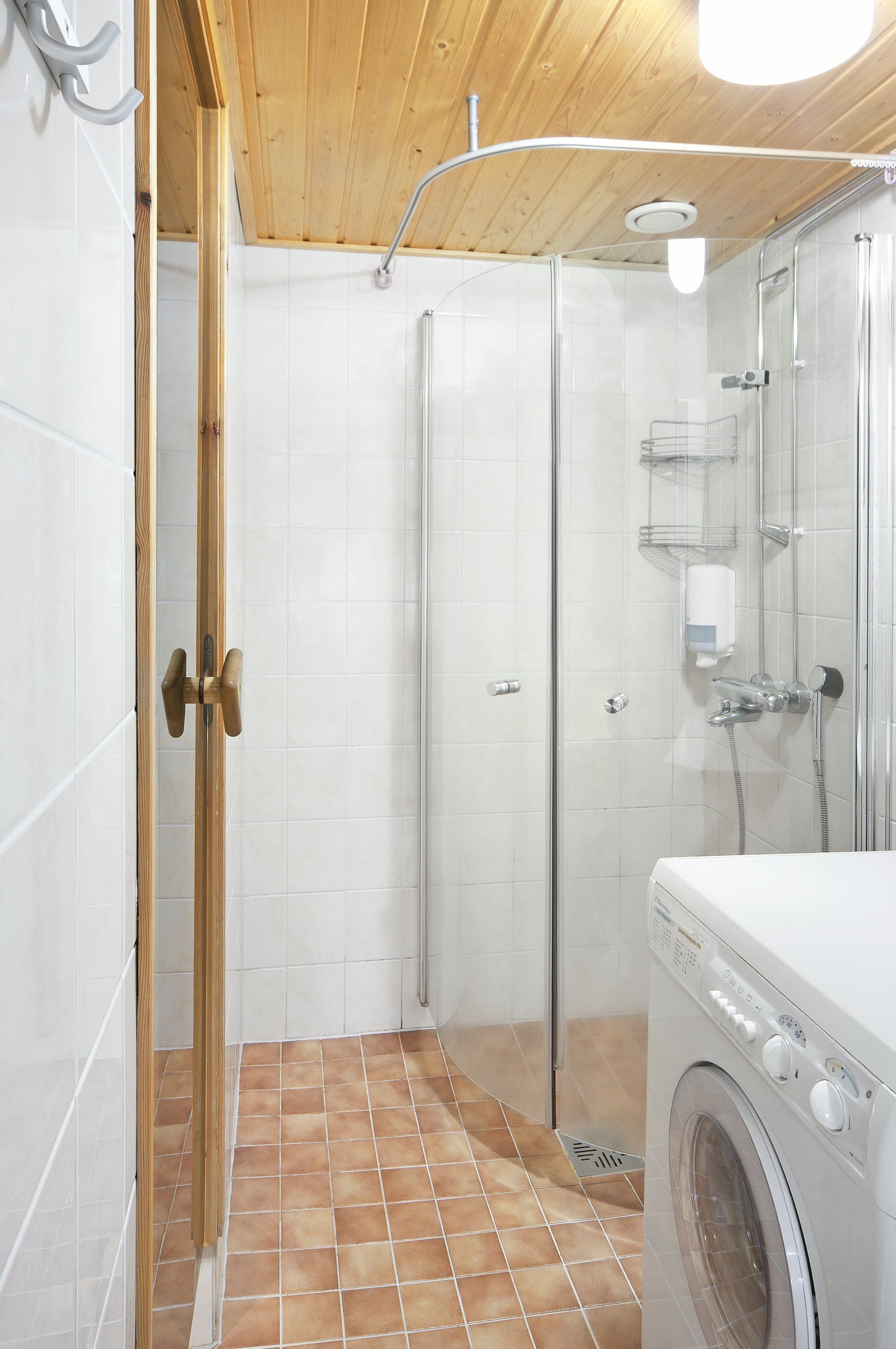 Une salle de bain avec une douche, des toilettes et un lave-linge.