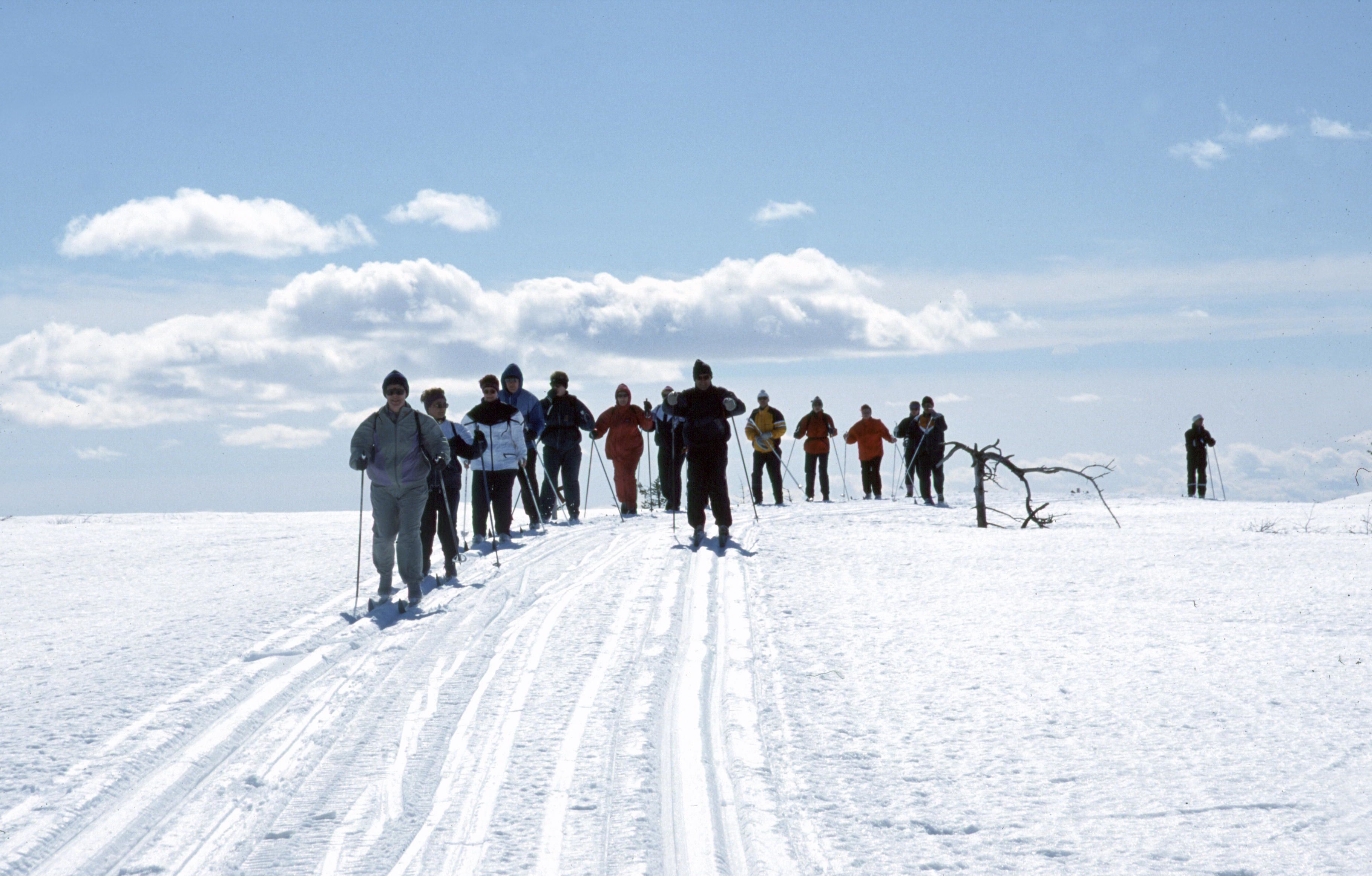 A group of people standing on a snowy slope with a clear sky.