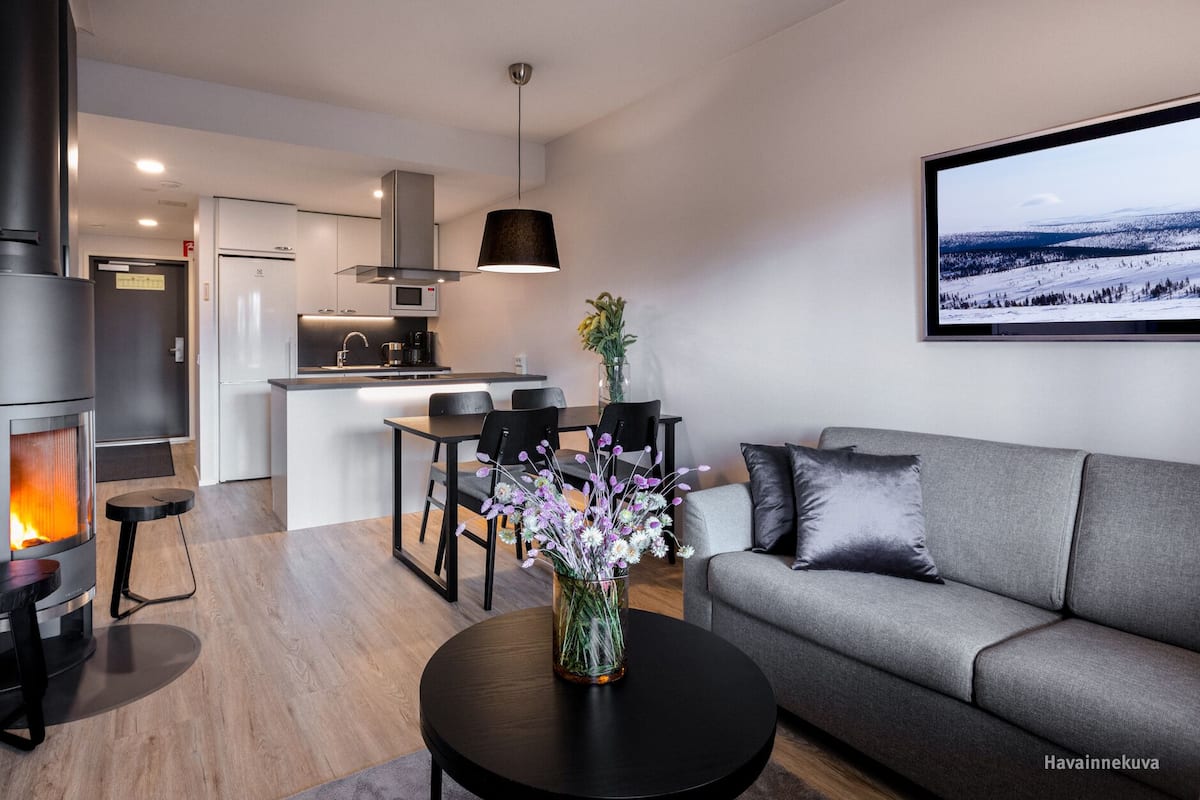 A modern living space with a central fireplace, a dining area, and a sofa.