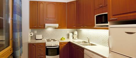 Ett kök med träskåp, en mikrovågsugn, en spis, ett handfat och en diskmaskin.