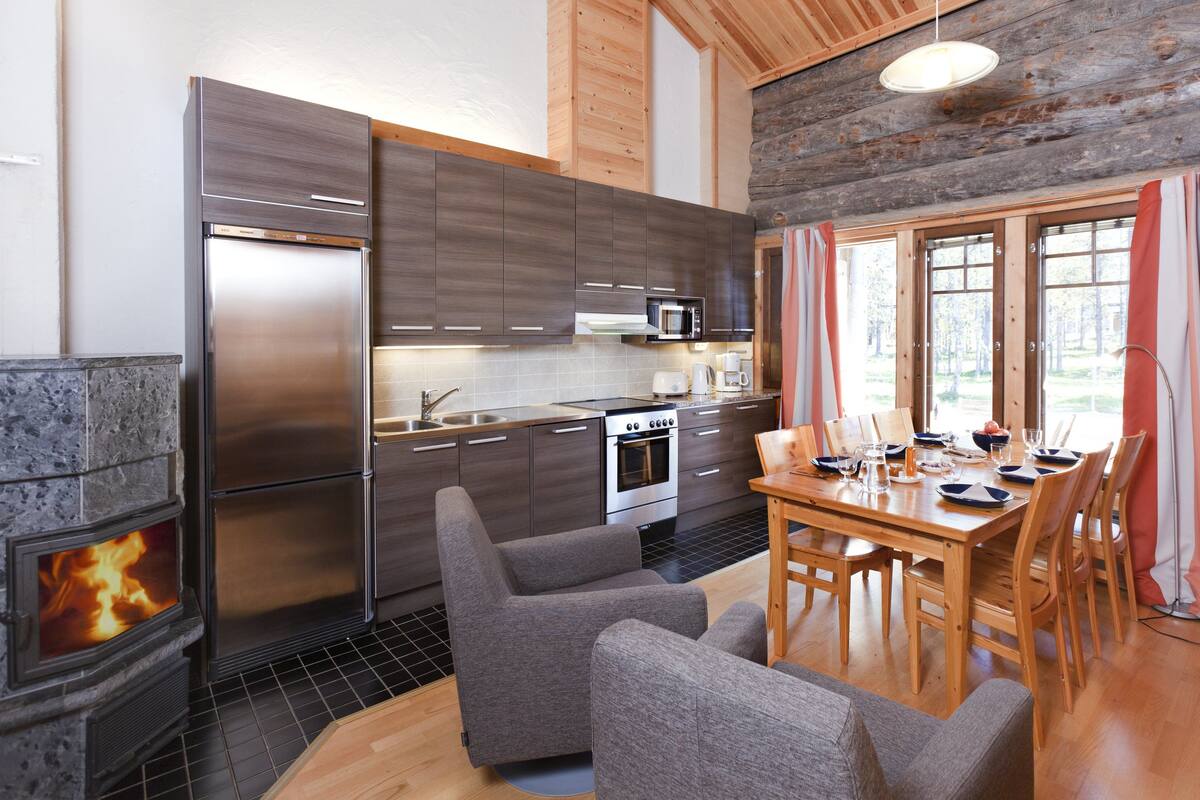 A modern kitchen with a built-in stove, stainless steel appliances, and a dining area with wooden furniture.