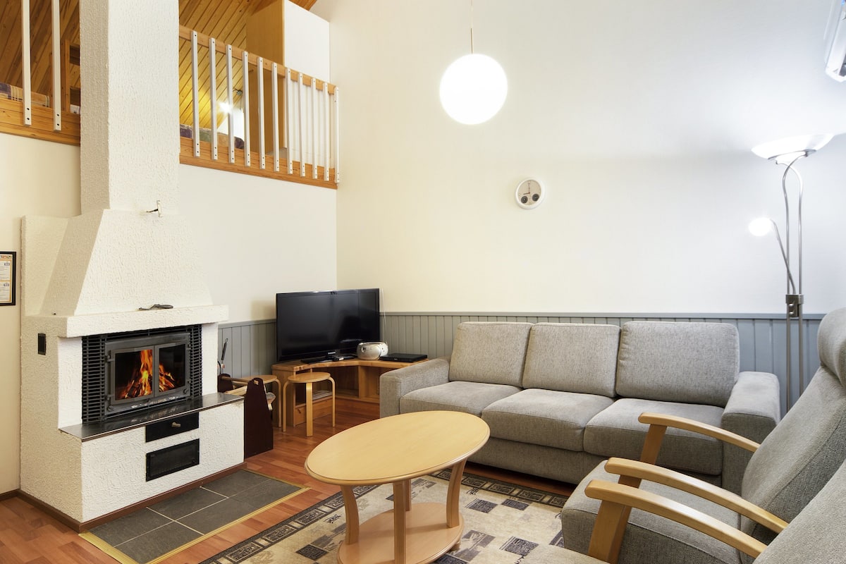 A living room with a fireplace, a sofa, a TV, and a wooden coffee table.
