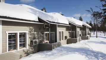 A row of cabins with snow-covered roofs and a clear sky.