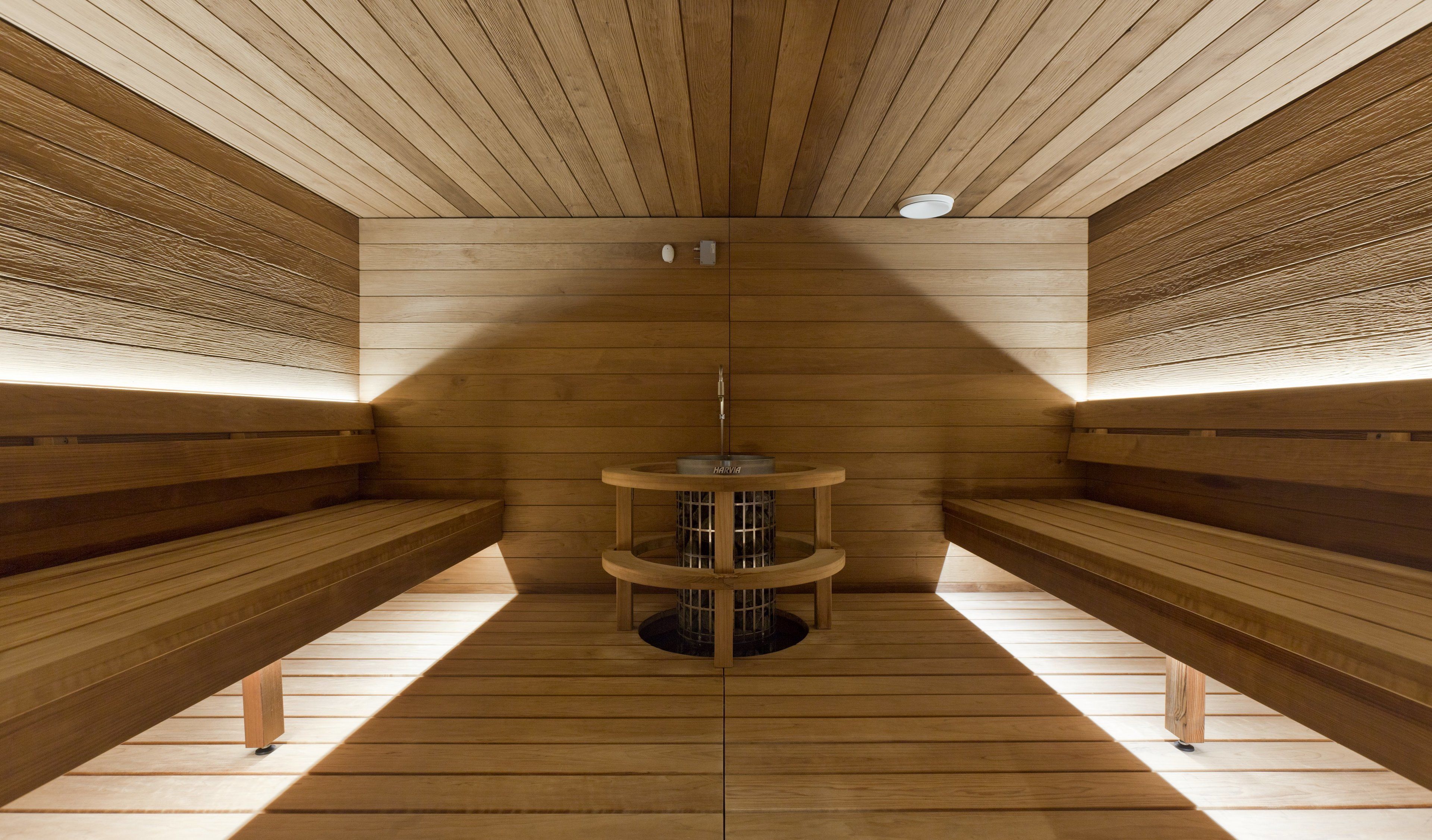 A sauna with wooden benches and a central heating unit.