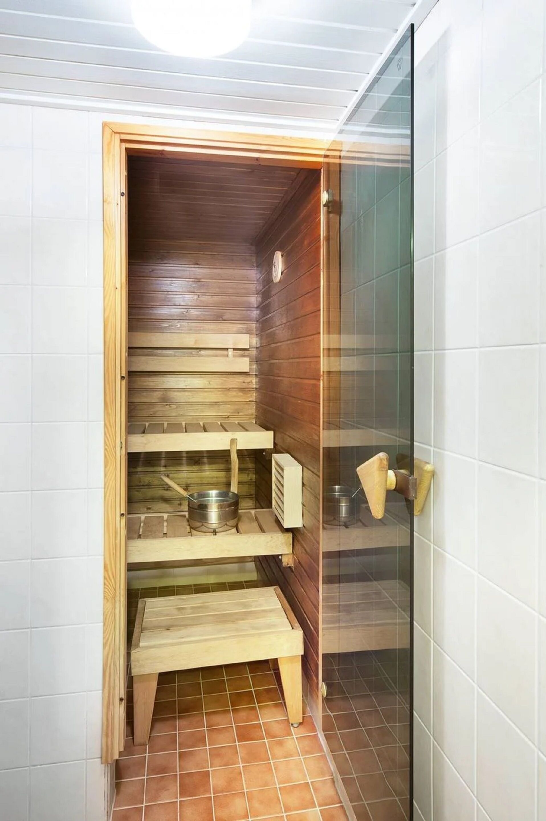 Eine Sauna mit Holzbänken und einem Metalltopf auf dem Boden.
