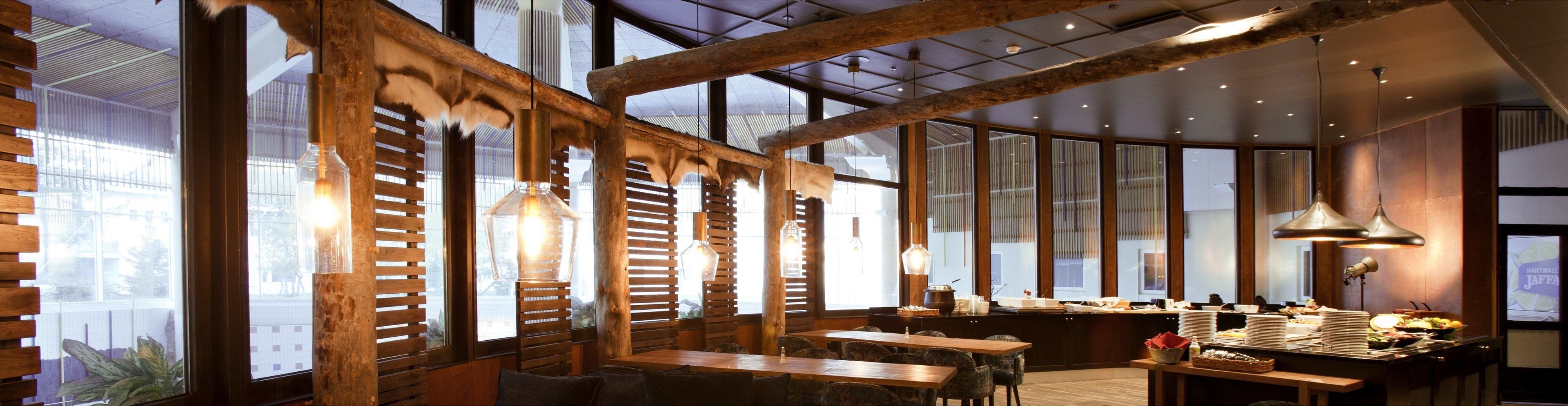 A restaurant with wooden slatted walls, hanging pendant lights, and a buffet area with various dishes.