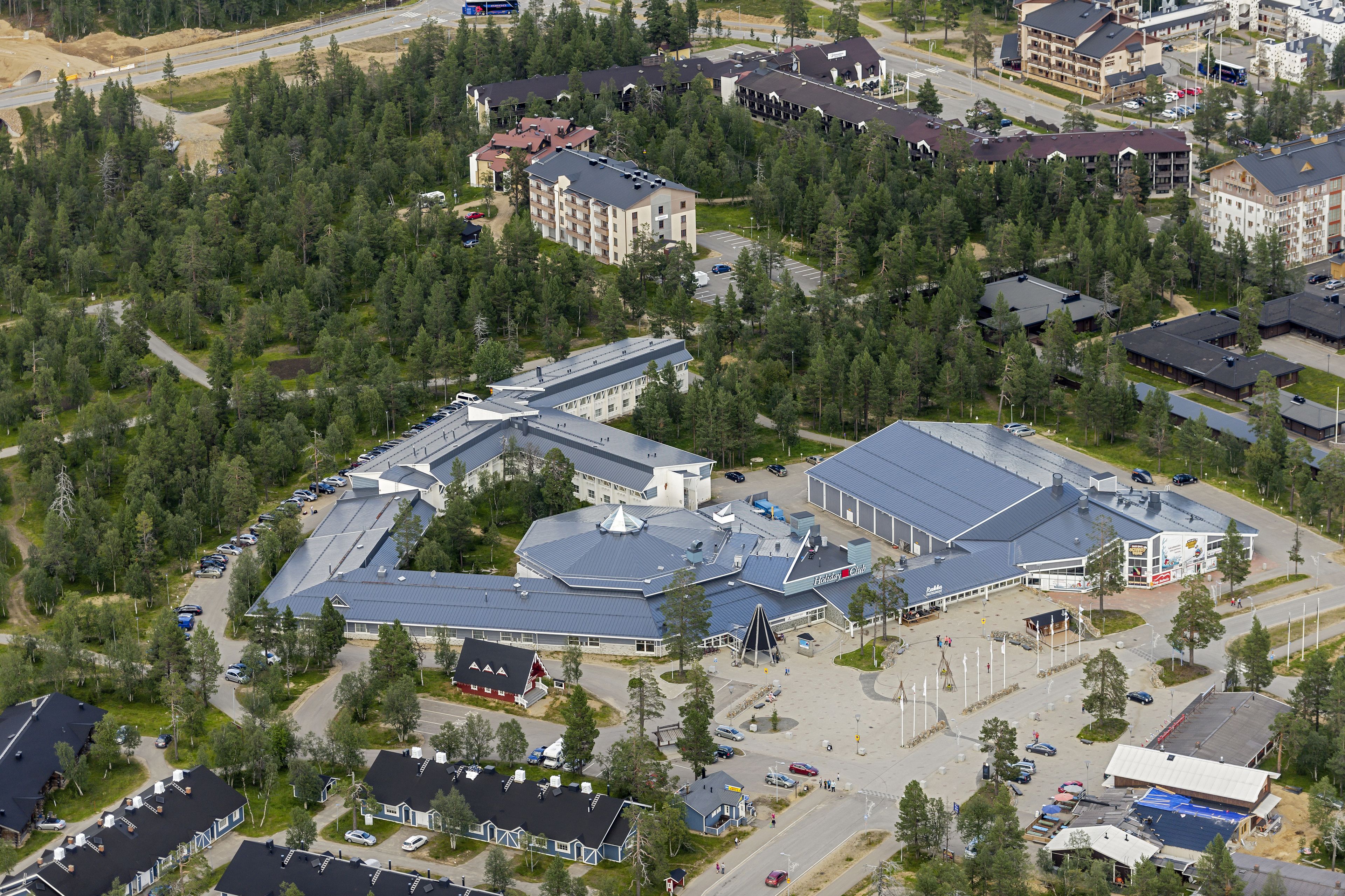 An aerial view of a hotel complex with multiple buildings, parking areas, and surrounding greenery.