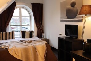A hotel room with a bed, a television, a lamp, and a painting on the wall.