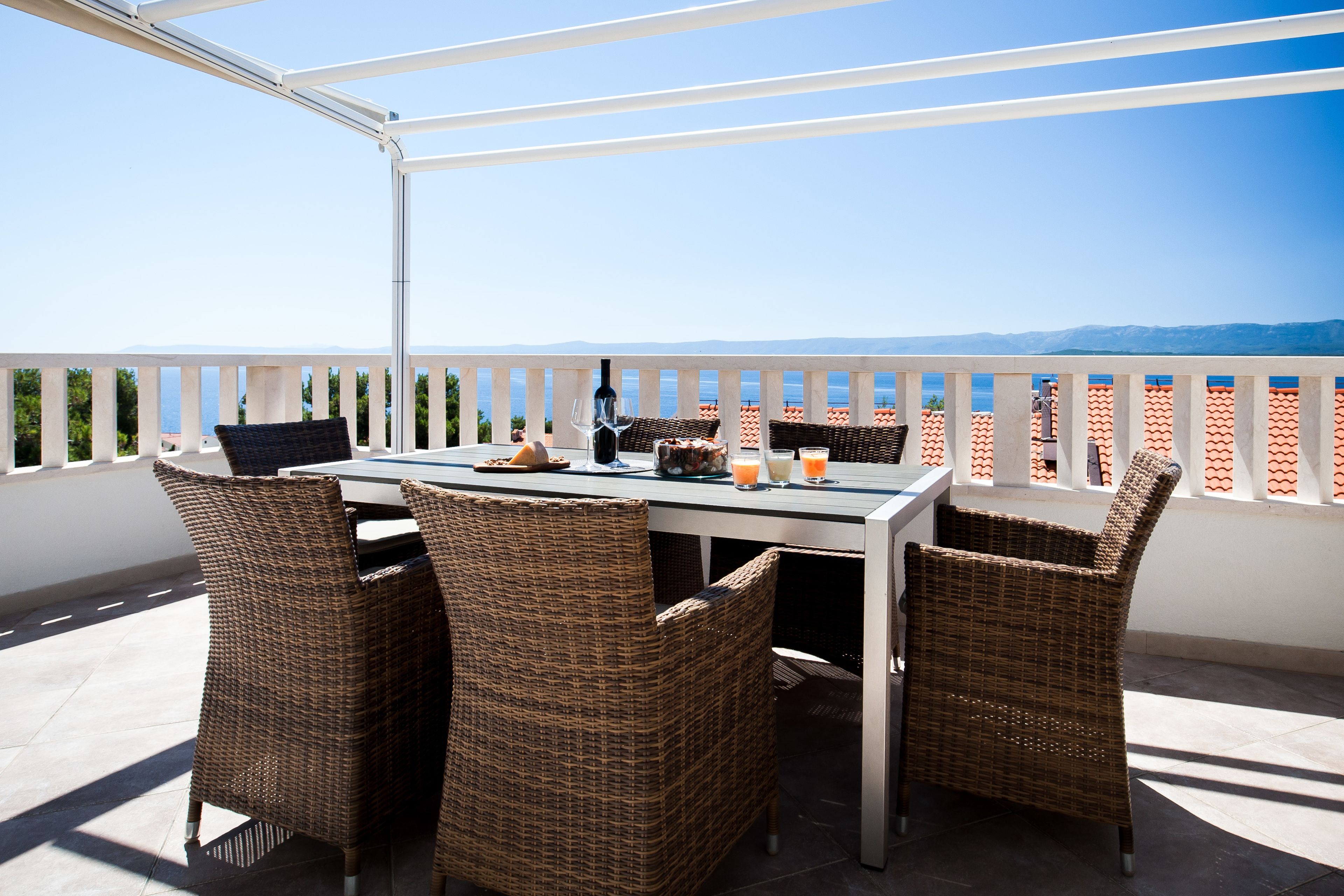 Eine Terrasse mit Tisch und Korbstühlen, die einen schönen Ausblick bietet.