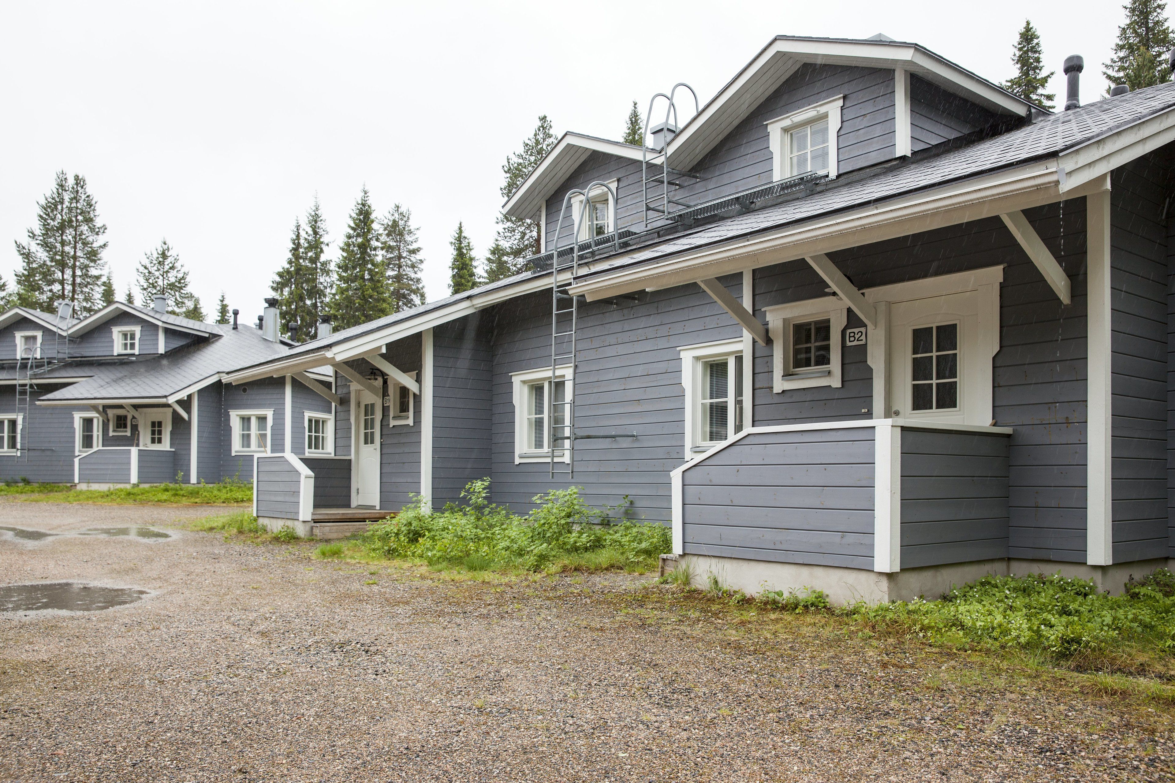 A row of two-story houses with a gravel driveway and overcast sky.