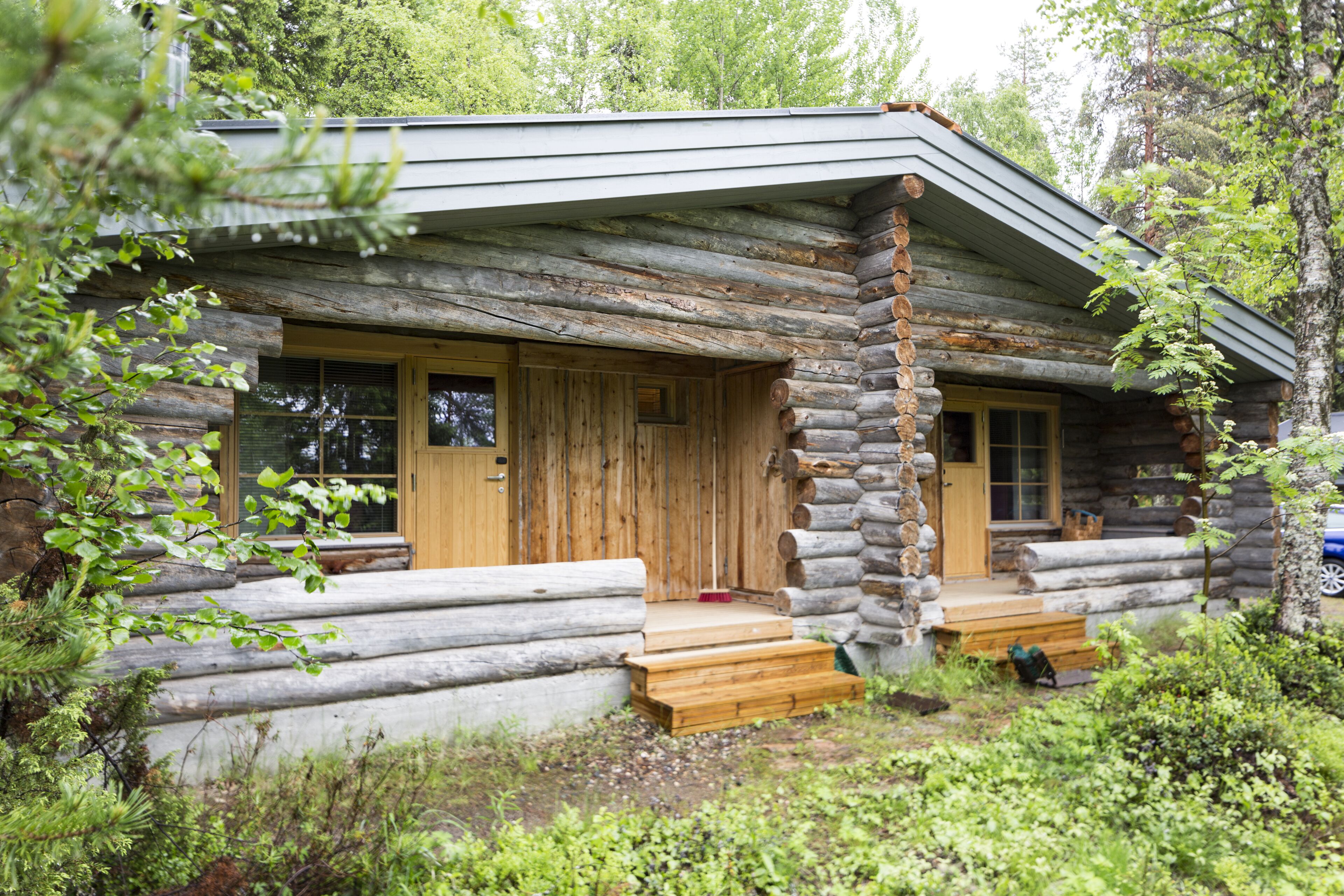 A log cabin with a wooden door, a front porch, and a window.