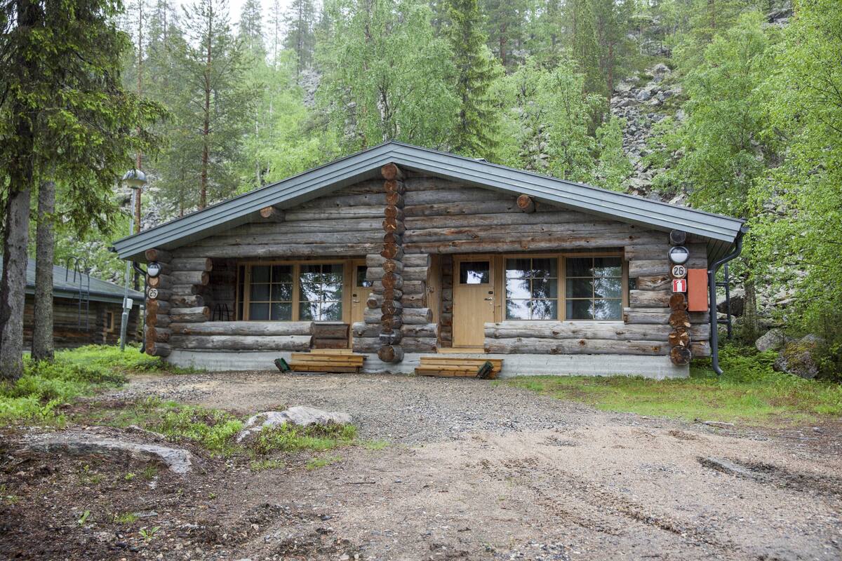 A log cabin with a simple, rustic design, featuring a front porch and a chimney.