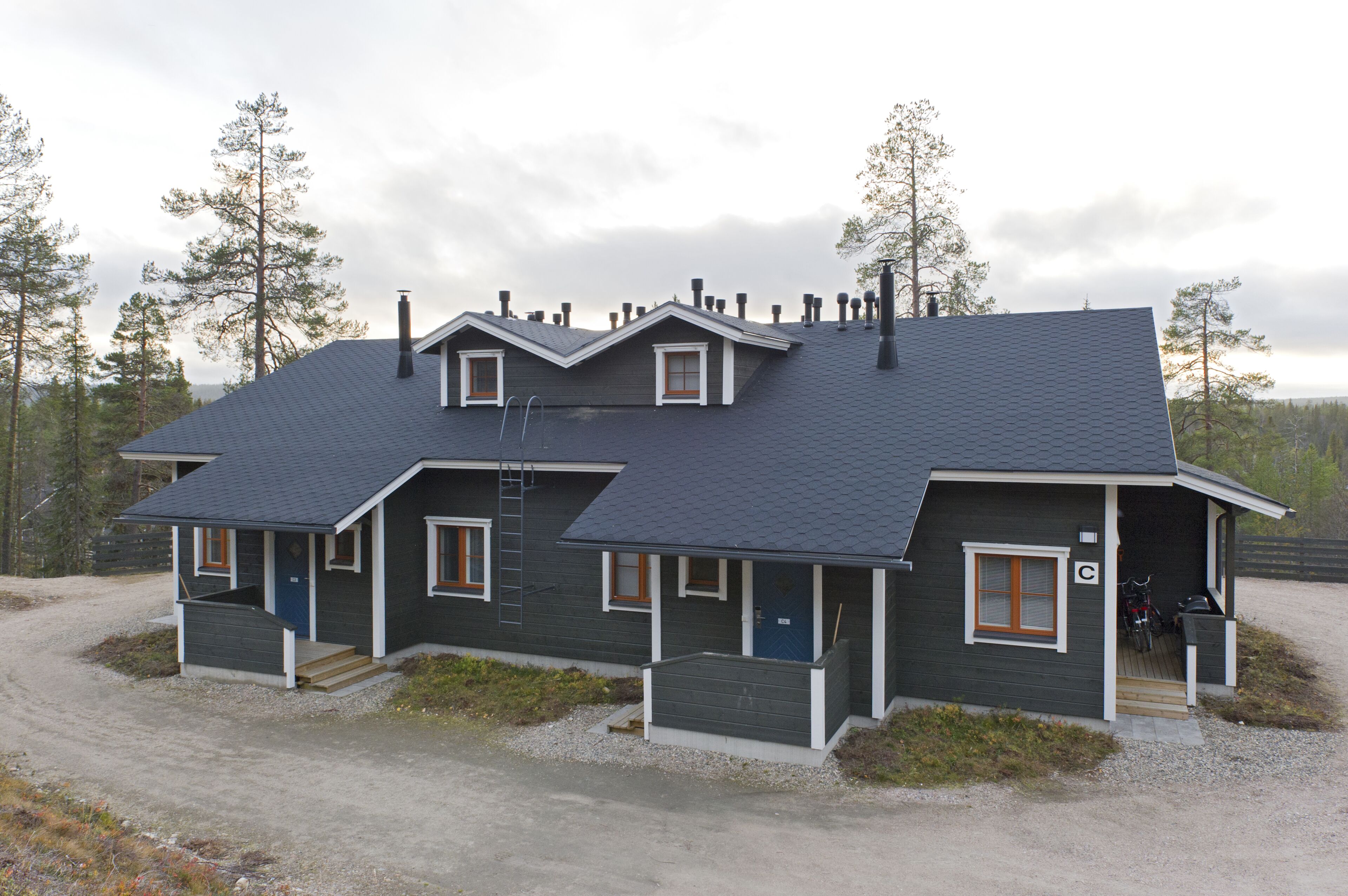 A two-story house with a dark grey exterior, a sloped roof, and a front porch.