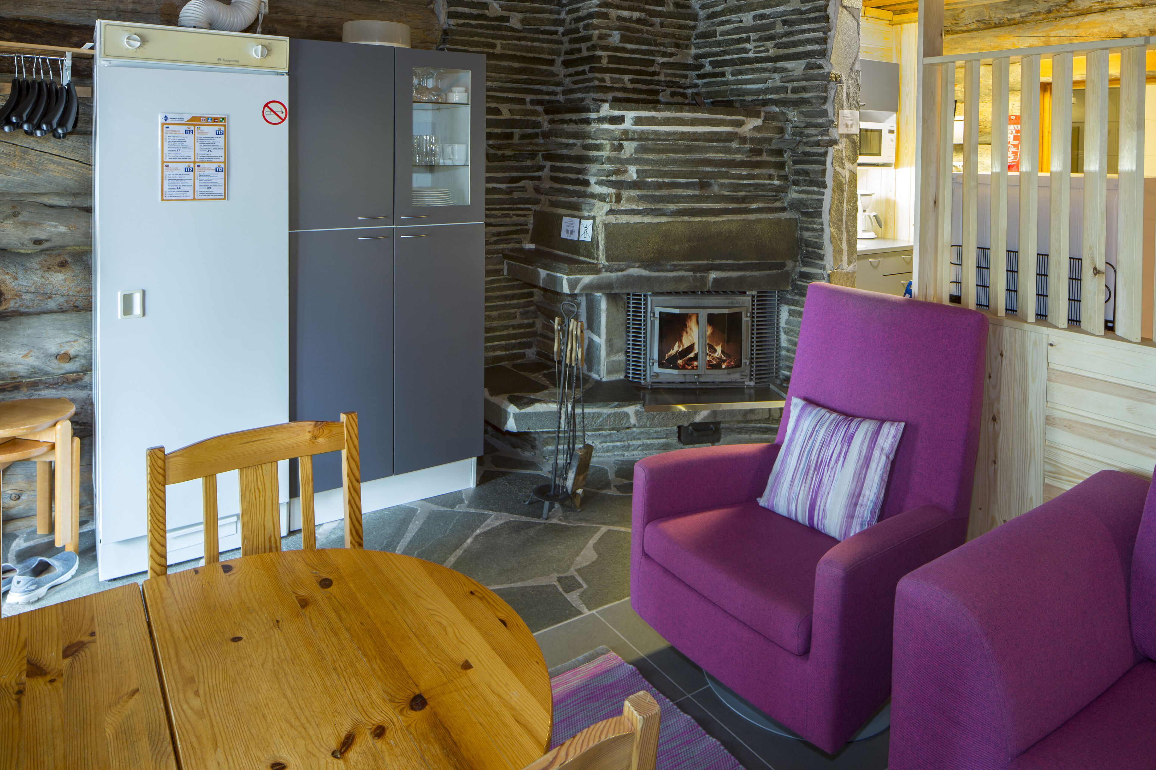 A cozy room with a stone wall, a fireplace, a purple sofa, and a wooden table.