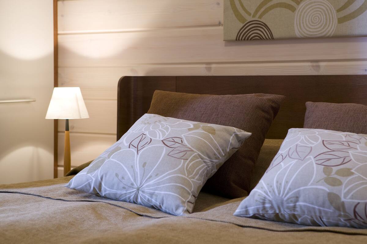 A neatly made bed with floral-patterned pillows and a wooden headboard.