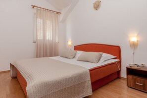 Un dormitorio con cama, mesita de noche, lámpara y ventana con cortinas.