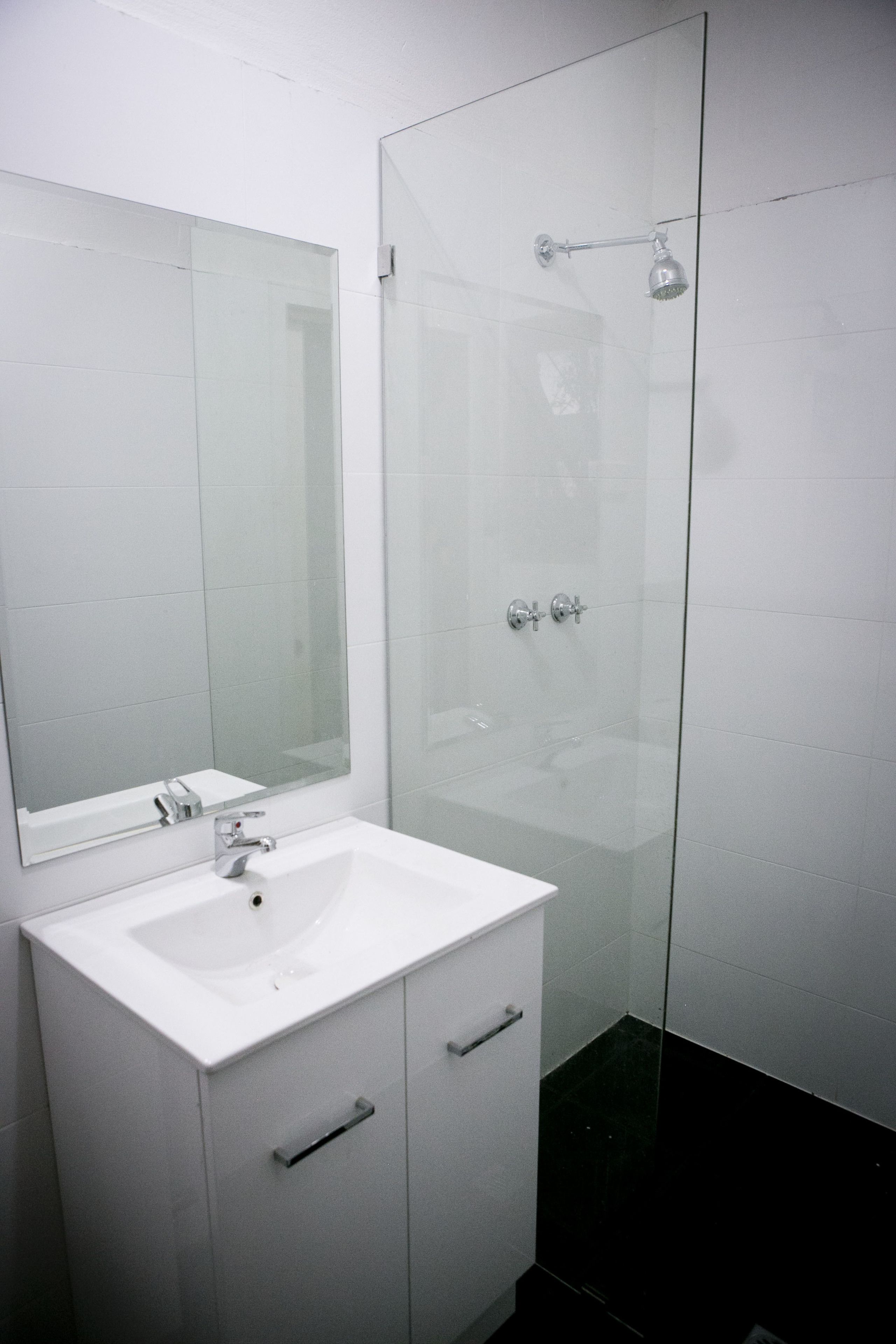 A modern bathroom with a white sink, a mirror, and a glass shower enclosure.