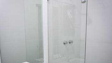 A modern bathroom with a white sink, a mirror, and a glass shower enclosure.