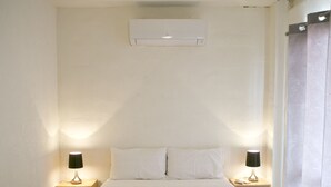 Et soveværelse med en seng, to sengeborde med lamper, en loftsvifte og en aircondition.