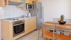 Una cocina compacta equipada con microondas, refrigerador, horno y una mesa de comedor con sillas.
