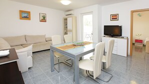 Una sala moderna con comedor, un sofá, un televisor y una mesita.