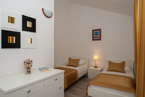 Habitació d'hotel amb dos llits, una taula de nit amb una làmpada, un petit quadre a la paret i un ramader decoratiu sobre la tauleta de nit.
