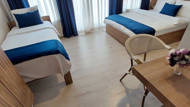 Ett hotellrum med två sängar, ett skrivbord i trä och en stol.