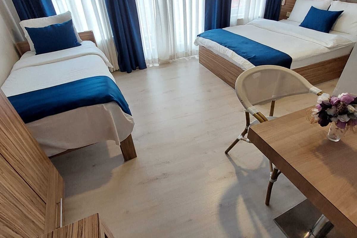 A hotel room with two beds, a wooden desk, and a chair.