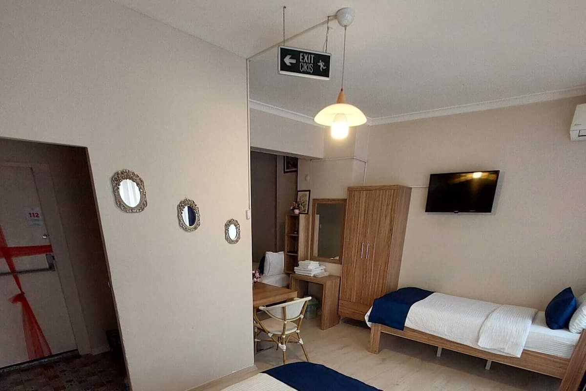 A hotel room with two beds, a TV, a desk, and a wardrobe.