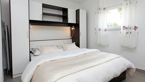 Un dormitorio con cama, estanterías empotradas y una ventana con cortinas.