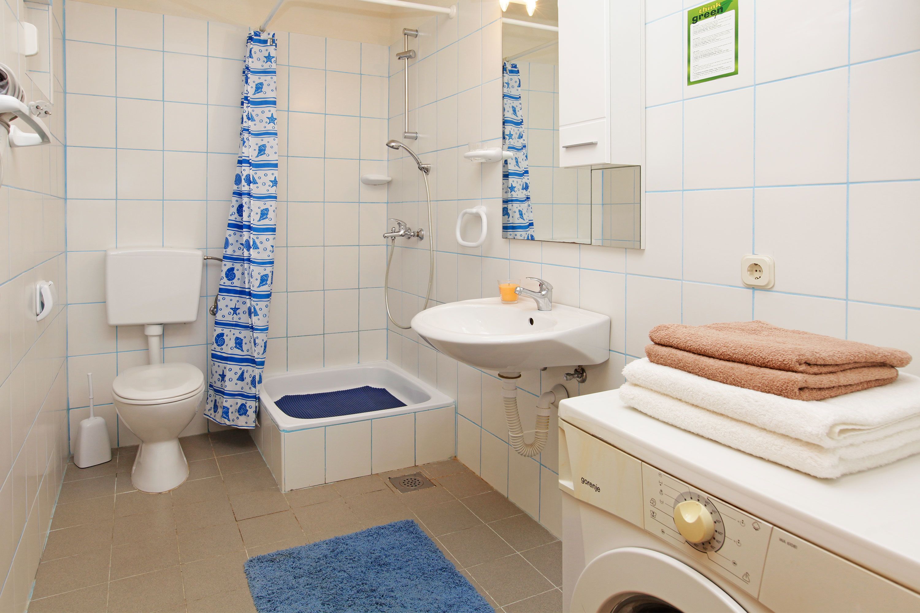 Une salle de bain équipée de toilettes, d’un bidet, d’un lavabo et d’un lave-linge.