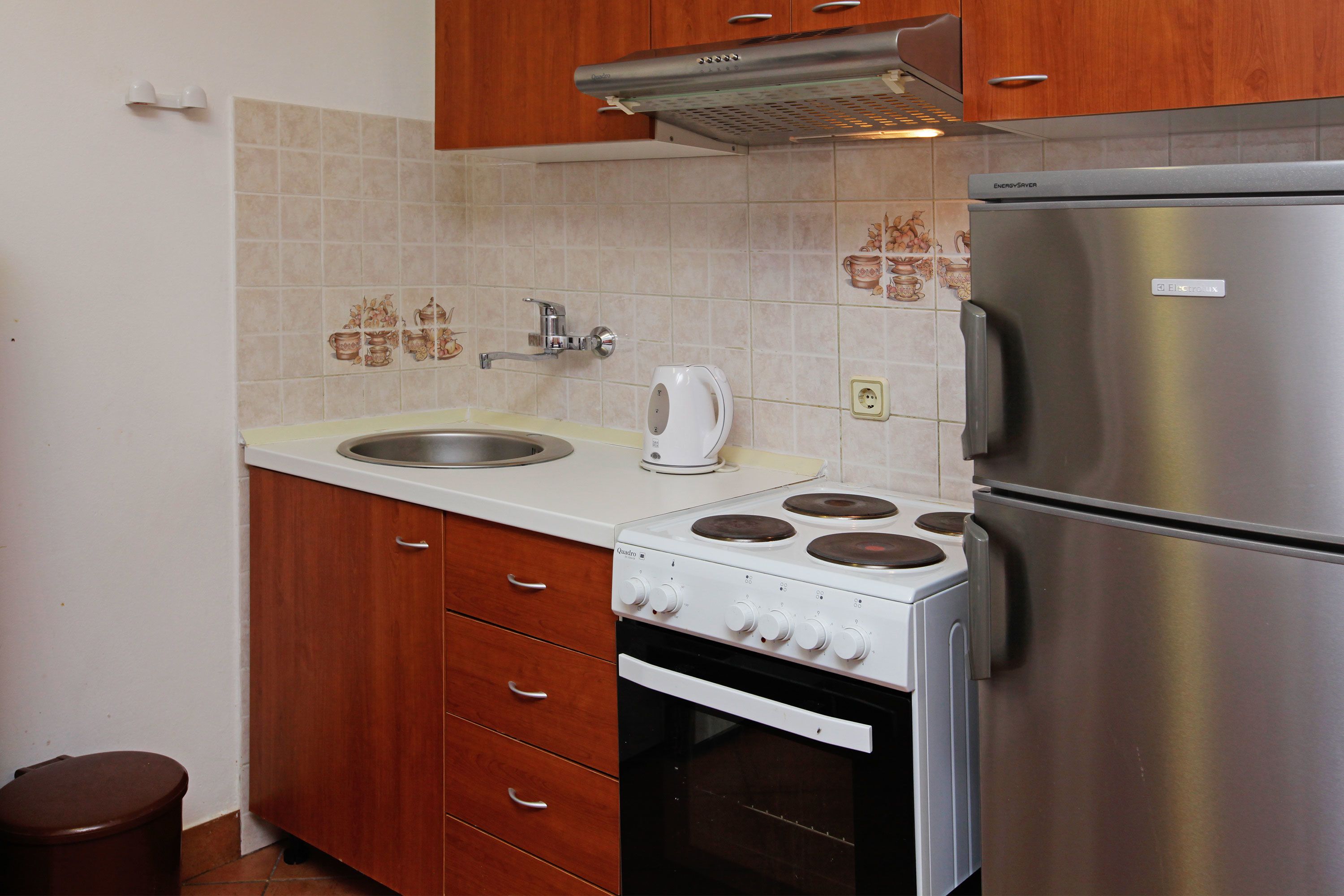 A compact kitchen with a stove, sink, and a refrigerator.