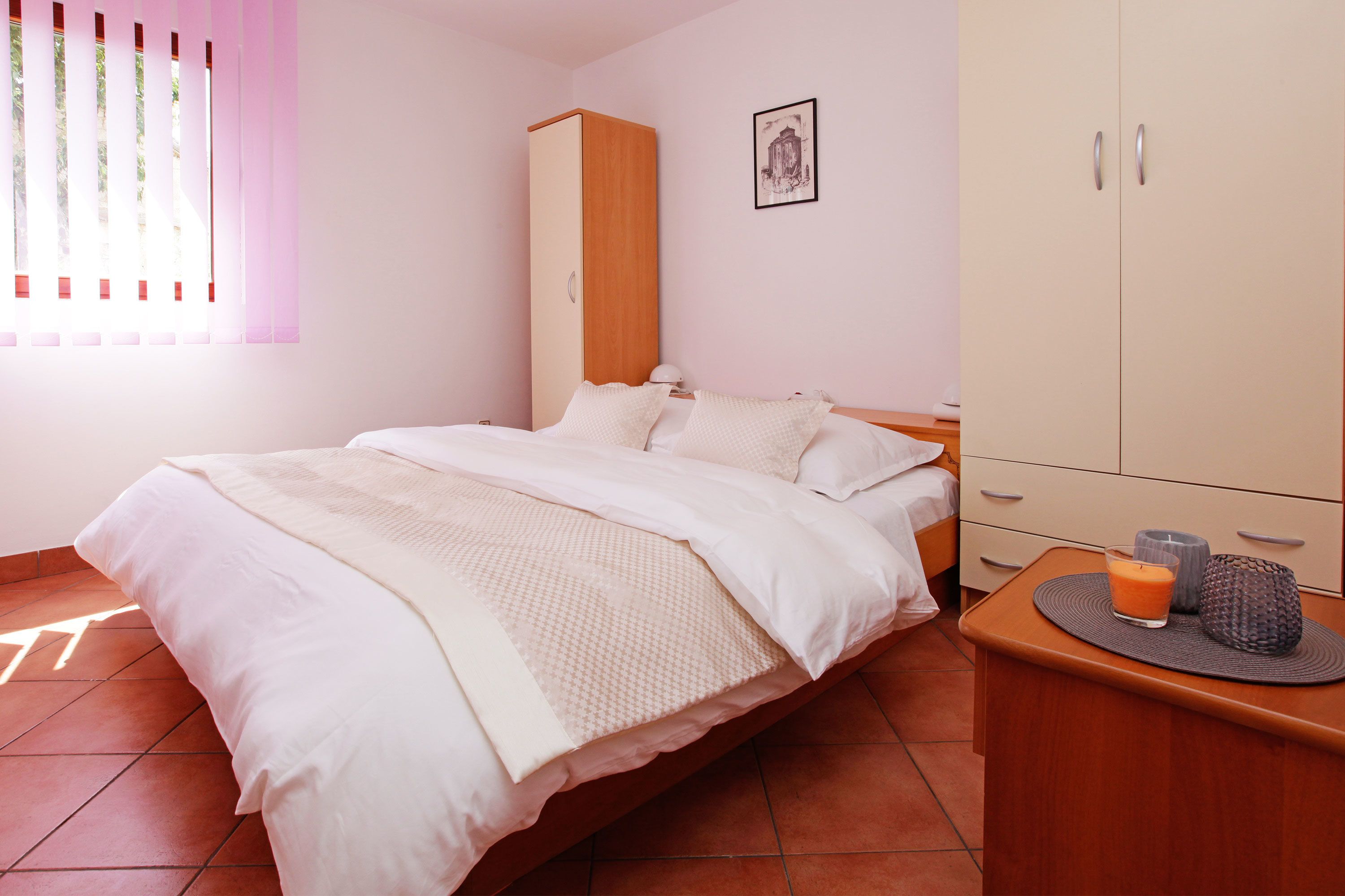 Une chambre à coucher avec un lit, une armoire et une table de chevet sur laquelle se trouve une bougie.