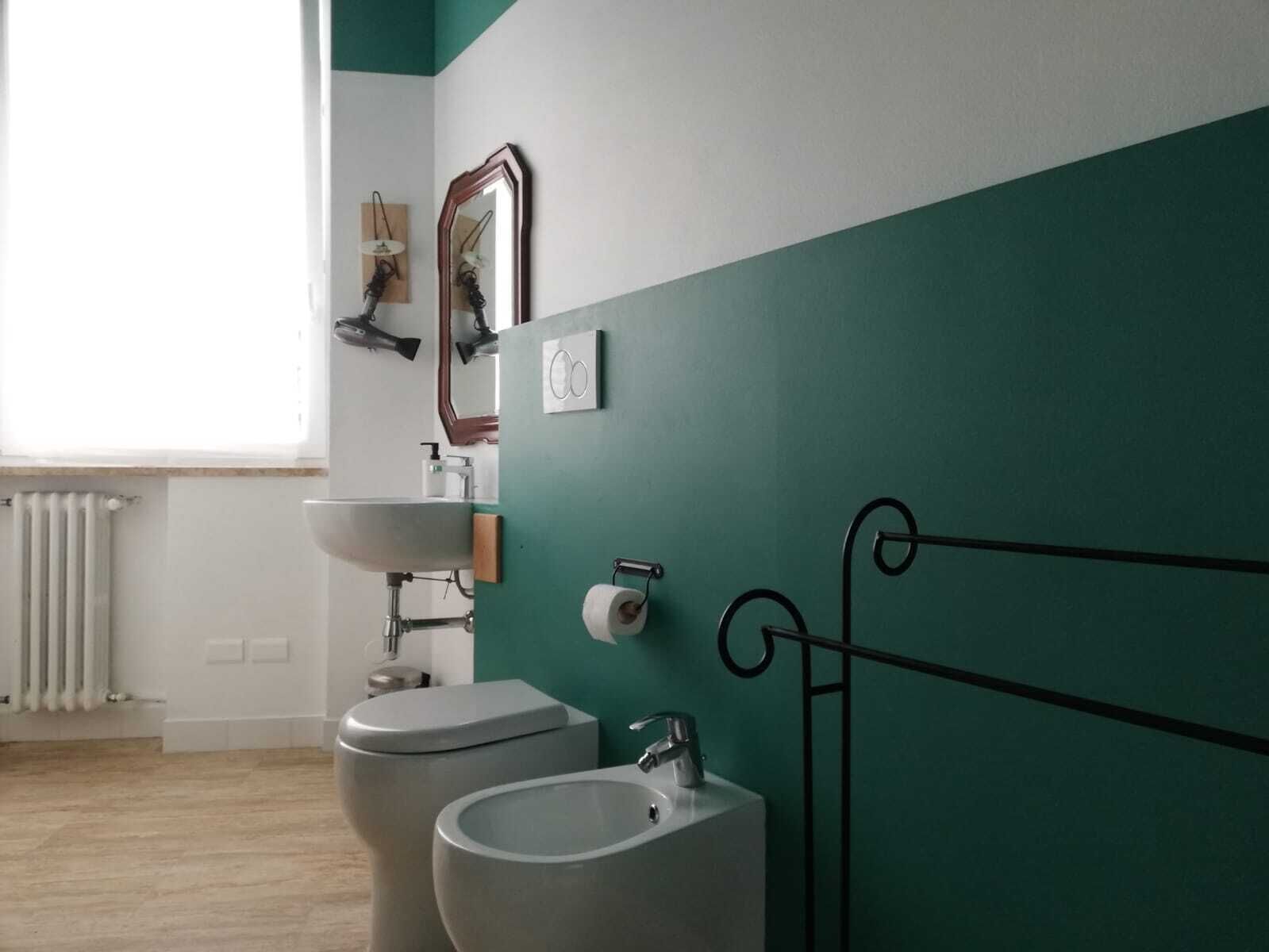 Un baño con inodoro, bidé y lavabo, un espejo y un radiador.