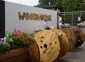 A wooden barrel seating area with a sign reading "WOODHOUSE" in the background. - La Cordata Accommodation - Woodhouse Bike Hotel (Cinisello Balsamo)