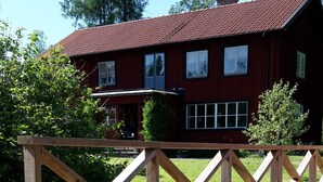 Une terrasse en bois avec une clôture en bois, une pile de coussins, un seau en bois et une plante en pot.