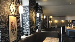 A cozy restaurant interior with a patterned wall, cushioned seating, and pendant lighting. - Homesly The George Hotel (Montrose)