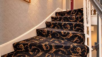 A staircase with ornate carpet patterns and wall-mounted lighting.