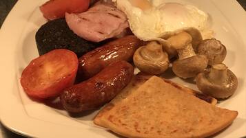 A plate of breakfast food including sausages, eggs, tomatoes, mushrooms, and toast.