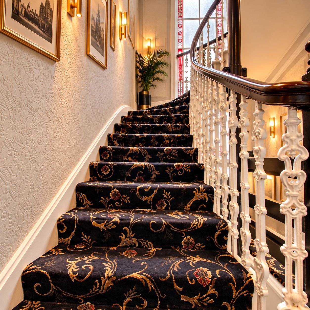Eine Treppe mit aufwendiger weißer Balustrade und einem gemusterten Teppich.