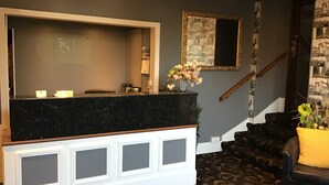 A reception area with a marble counter, a mirror, and a staircase. - Homesly The George Hotel (Montrose)