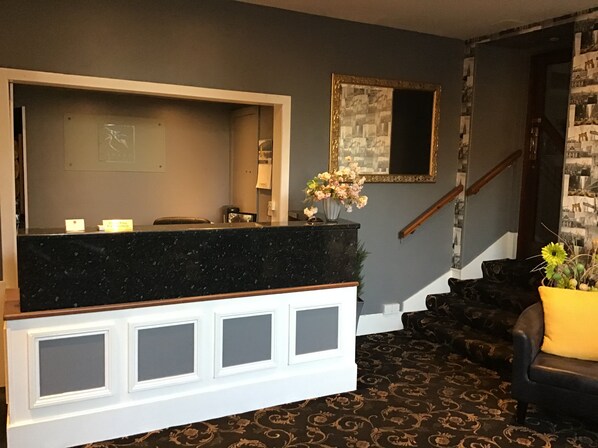 A reception area with a marble counter, a mirror, and a staircase. - Homesly The George Hotel (Montrose)