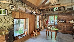 Un intérieur rustique avec des murs en pierre, des poutres apparentes, un lustre, un meuble à vin et une table à manger.