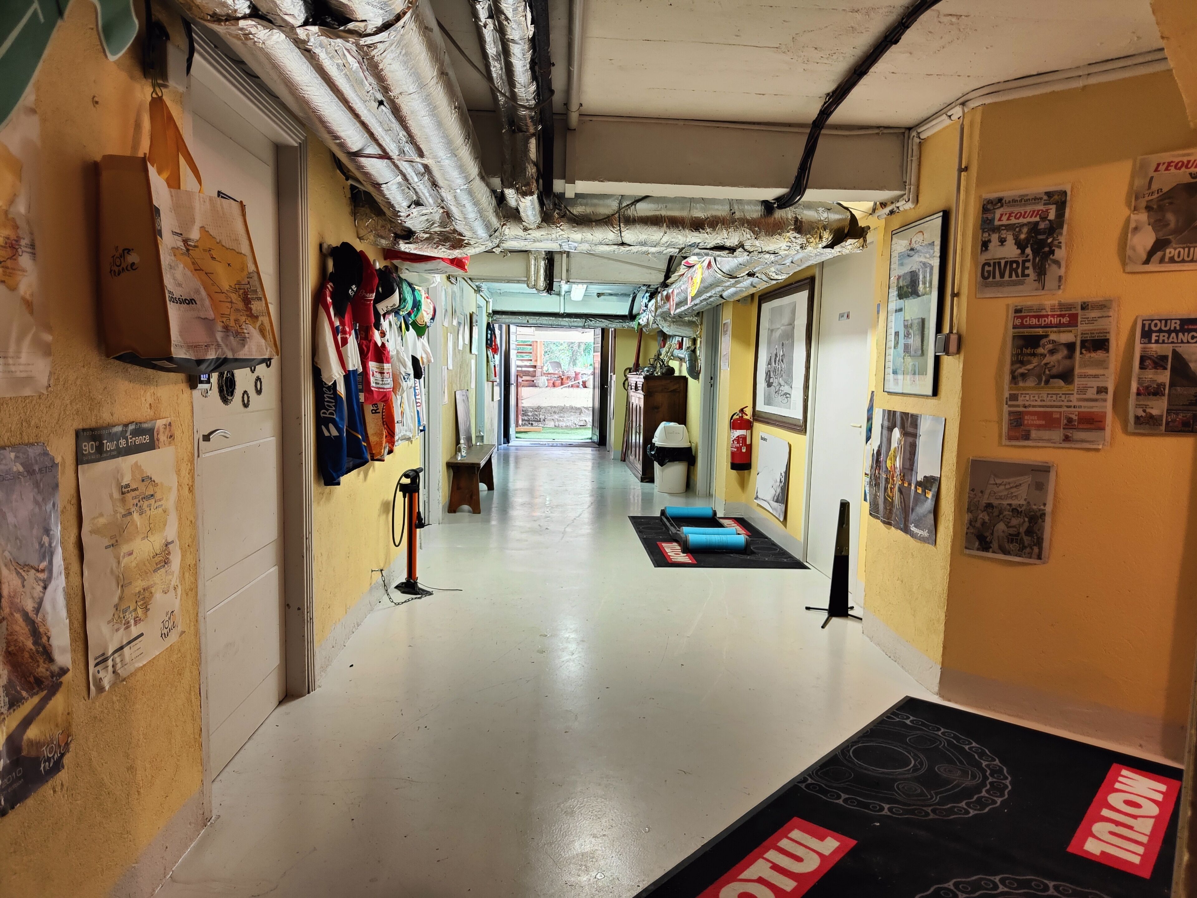 A hallway with posters, a fire extinguisher, and a mat with 'MOTUL' branding.